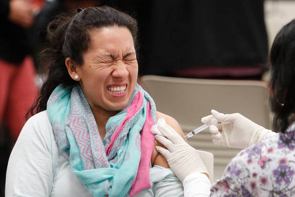 Ana Farfan reacts to getting an influenza vaccine shot at Eastfield College in Mesquite, Texas, ...