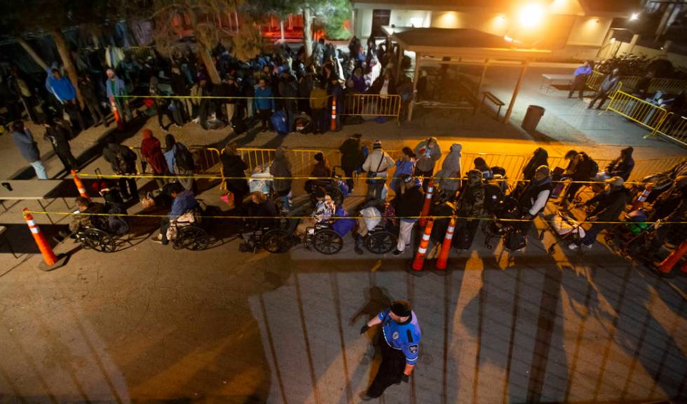 People wait in line to check in and get a sleeping mat at the Courtyard Homeless Resource Cente ...