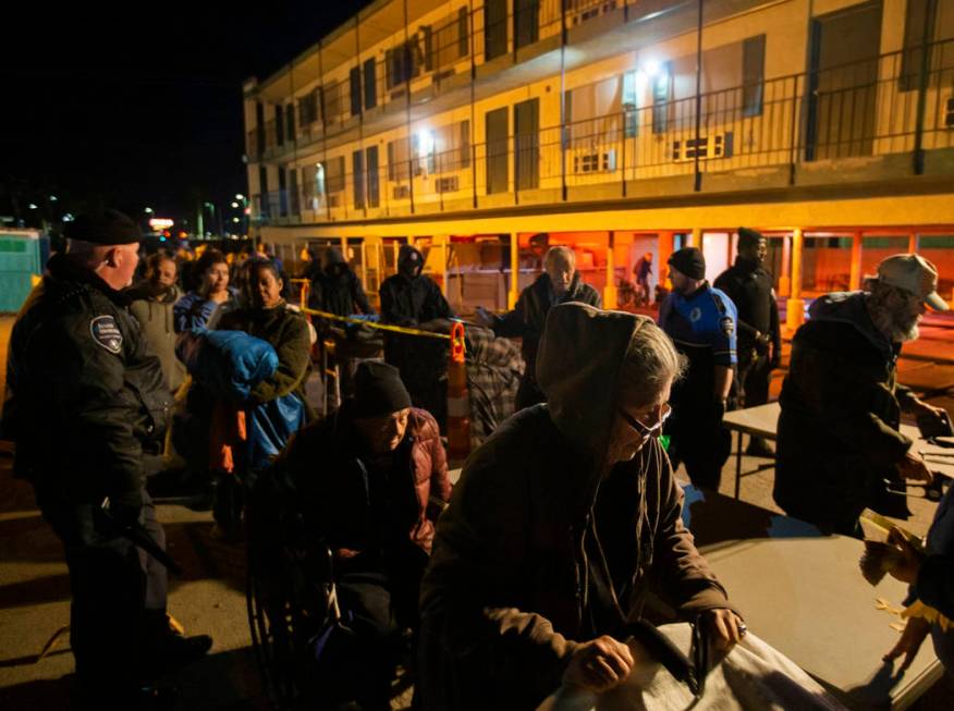 People wait in line to check in and get a sleeping mat at the Courtyard Homeless Resource Cente ...