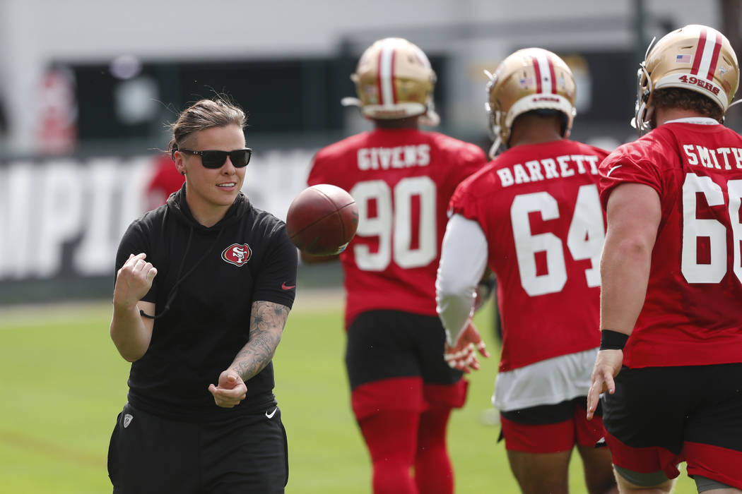 San Francisco 49ers offensive assistant coach Katie Sowers, left, tosses a ball to players duri ...