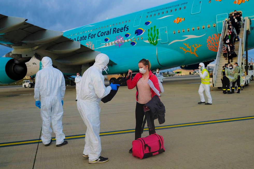 FILE - In this Feb. 2, 2020 file photo, a worker wearing a protective suit checks the luggage o ...