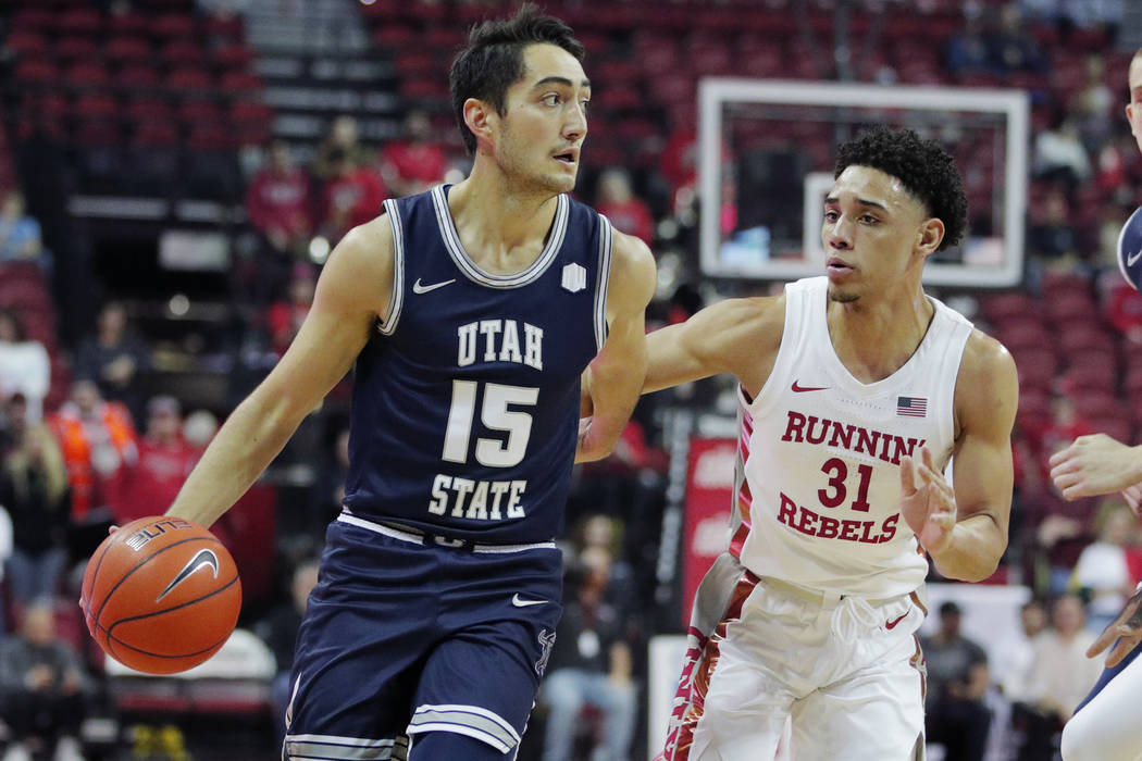 Utah State's Abel Porter (15) drives around UNLV's Marvin Coleman (31) during the first half of ...