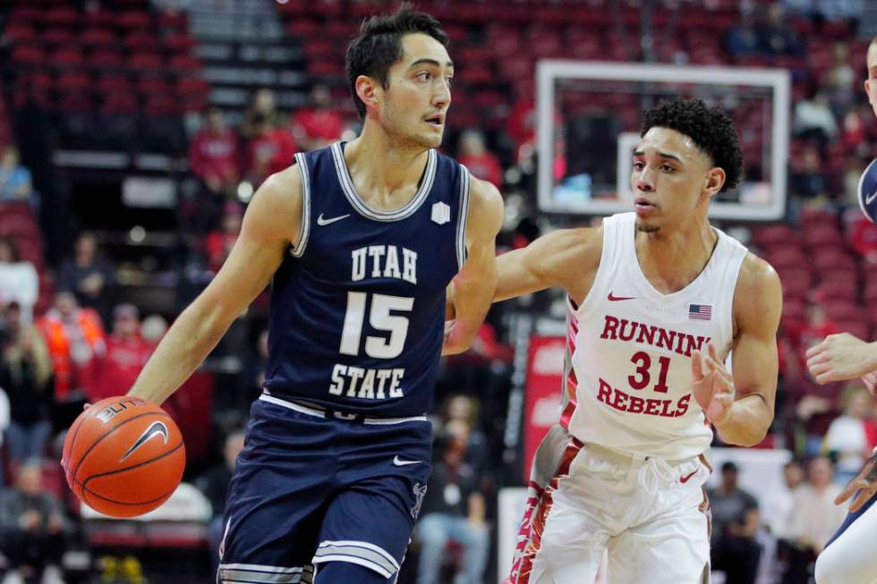 Utah State's Abel Porter (15) drives around UNLV's Marvin Coleman (31) during the first half of ...