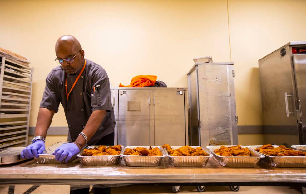 Sarif El-Amin, of Three Square food bank, packages fried chicken and other surplus banquet food ...