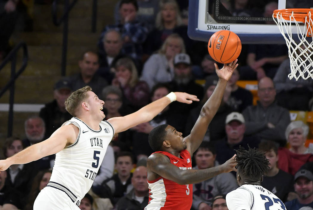 UNLV guard Amauri Hardy (3) shoots as Utah State guard Sam Merrill (5) and center Neemias Queta ...