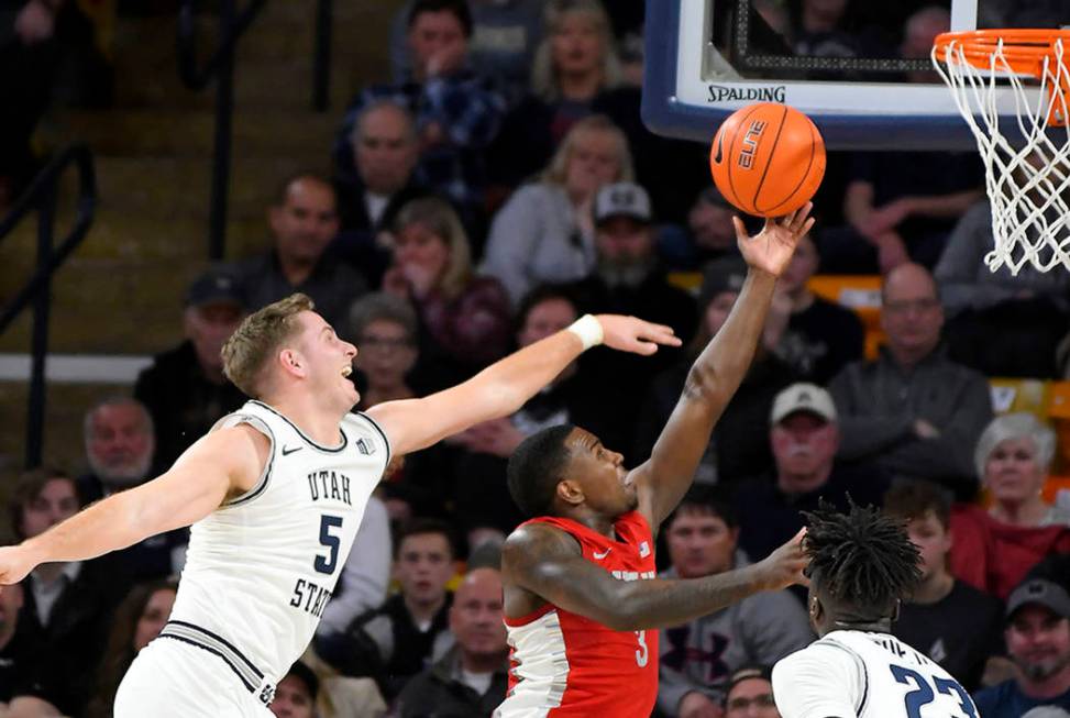 UNLV guard Amauri Hardy (3) shoots as Utah State guard Sam Merrill (5) and center Neemias Queta ...