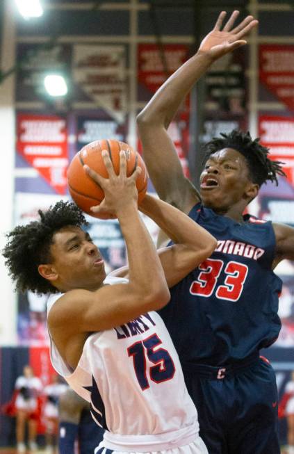 Liberty junior forward Greyson Montgomery (15) gets fouled on the way to the rim by Coronado so ...