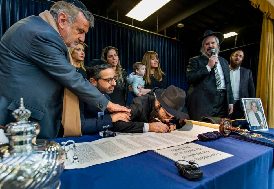 Rabbi Dovid Bressman, center, as Sofer inscribes the last words on a new Torah surrounded Rabbi ...