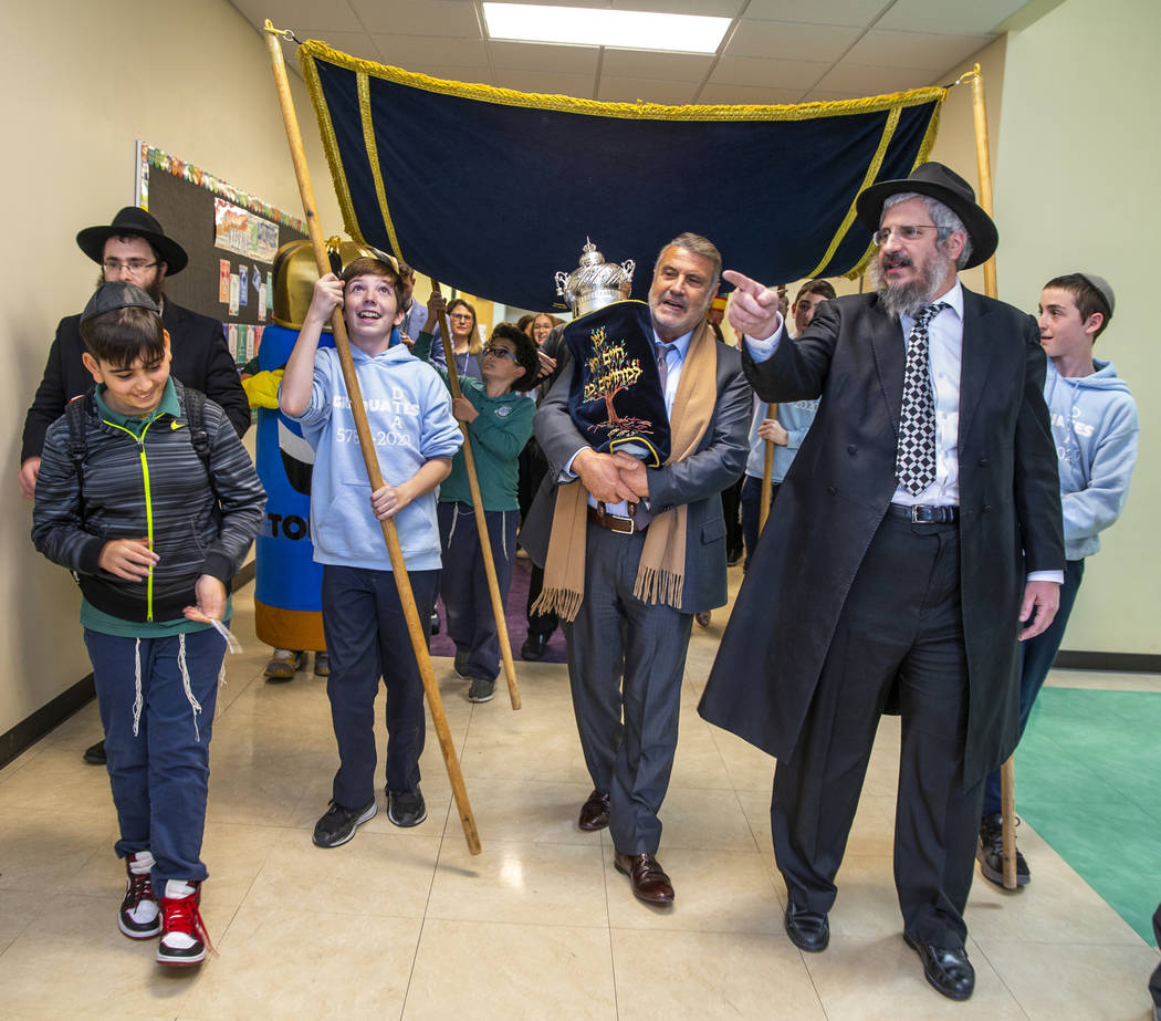 Sonny Kahn, center, carries a newly inscribed Torah beside Rabbi Shea Harlig, right, as they pr ...