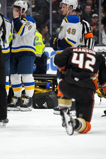 St. Louis Blues defenseman Vince Dunn, left, wipes his faces as Anaheim Ducks defenseman Josh M ...