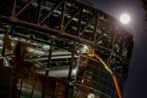 The Snow Moon rises behind Allegiant Stadium as a worked continues welding on the structure on ...