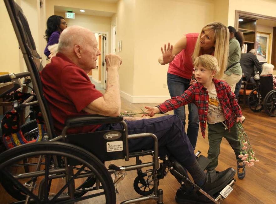 Jack Jones, 4, hands out Valentine's flowers to Jeff Nichol as his mother Jenny looks on at Poe ...