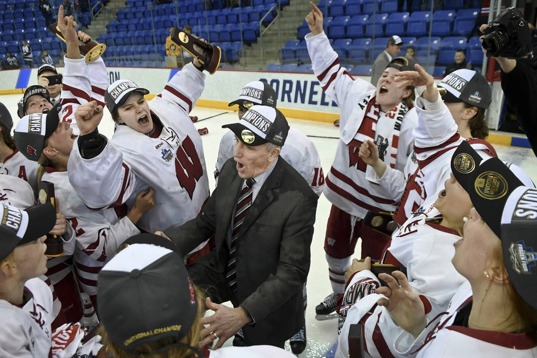 Wisconsin coach Mark Johnson is surrounded by his team as they celebrate after defeating Minnes ...