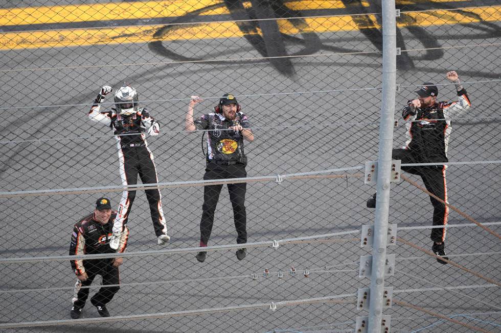 Noah Gragson, left, and crew members celebrate by climbing onto the grandstands safety fence af ...