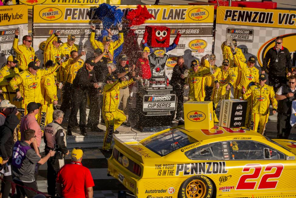 Crew members spray Joey Logano (22) with beer as he exits the car to celebrate in the winner's ...