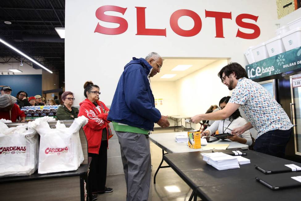 Nation Graca, right, site leader, hands out voting card to Reginald Bates of Las Vegas, during ...