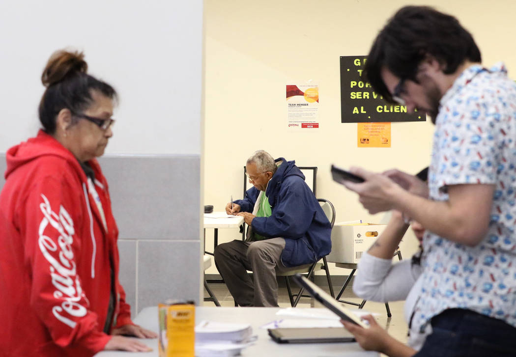 Nation Graca, right, site leader, registers Renee Cazares, left, of Las Vegas as Reginald Bates ...