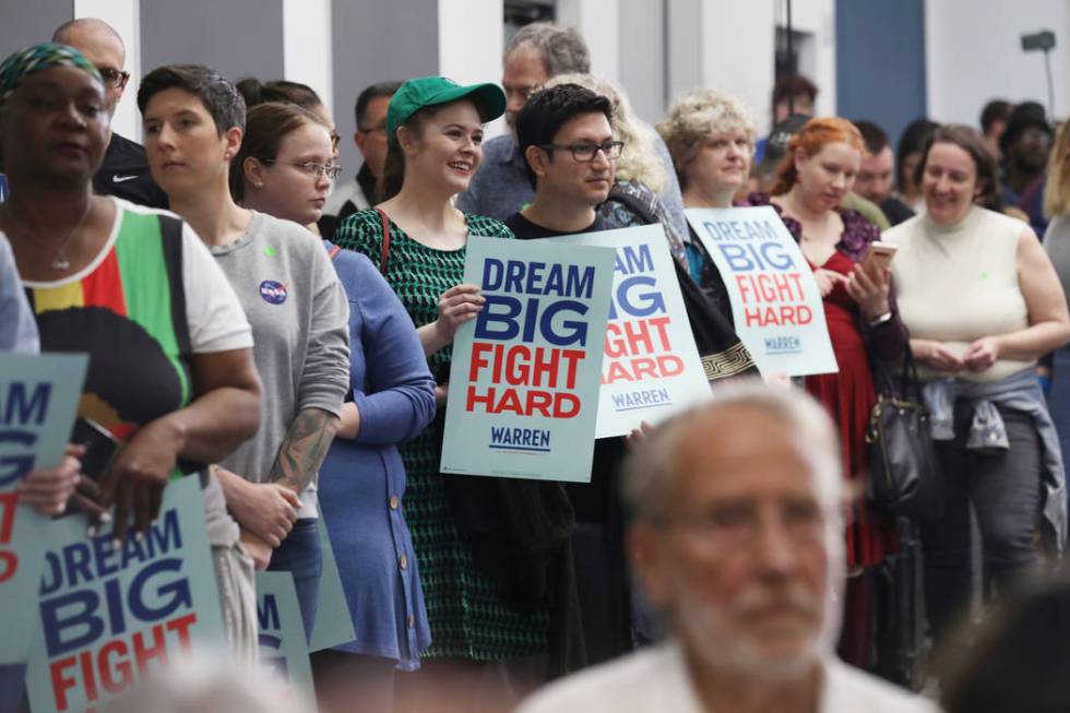 Supporters hold signs and listen as Sen. Elizabeth Warren speaks ahead of a town hall at Colleg ...