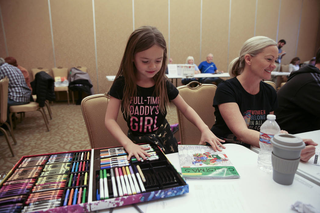 Madden Johlfs, 5, colors while her mother Susan Johlfs, 49, checks in for early voting in the N ...