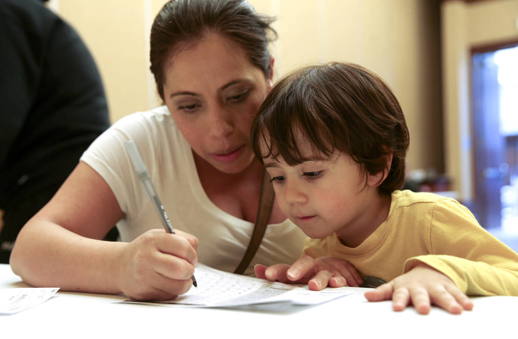 Alexander Silva, 3, of Henderson watches his mother Marcela fill out her ballot during early vo ...