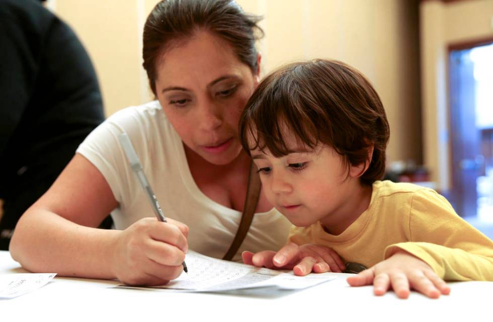 Alexander Silva, 3, of Henderson watches his mother Marcela fill out her ballot during early vo ...