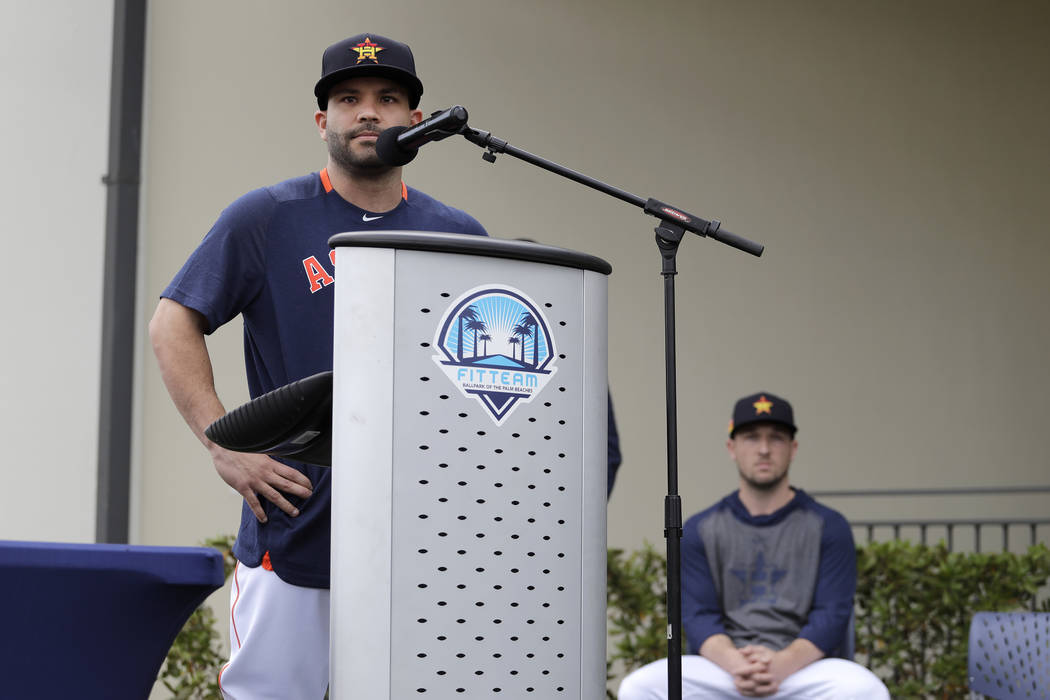 Houston Astros' Jose Altuve speaks at a podium as teammate Alex Bregman, seated right, looks on ...