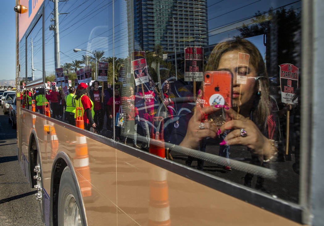 An RTC transit rider takes a photo of workers from seven Station Casinos' properties reflected ...