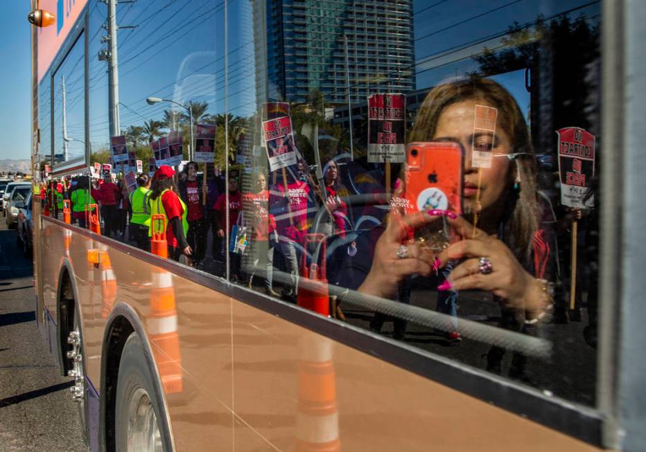 An RTC transit rider takes a photo of workers from seven Station Casinos' properties reflected ...