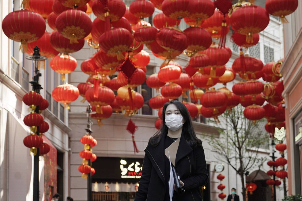 A woman wearing mask, walks on a street in Hong Kong, Thursday, Feb. 20, 2020. More than 100 Ho ...
