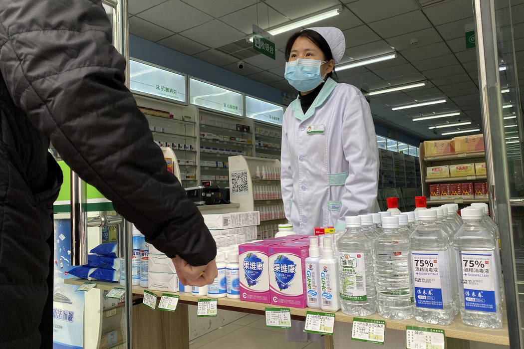 A pharmacy worker attends to visitors at the store entrance in Beijing, China on Thursday, Feb. ...