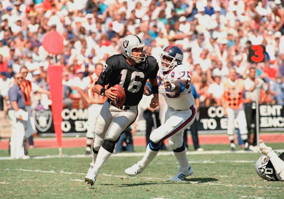 Los Angeles Raiders quarterback Jim Plunkett (16) is dogged by New York Giants George Martin du ...