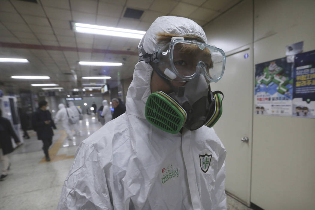 A workers wearing protective gears arrives to spray disinfectant as a precaution against the co ...