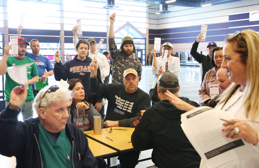 Lori Church, right, precinct chair, counts as Democratic caucus-goers raise their voting cards ...