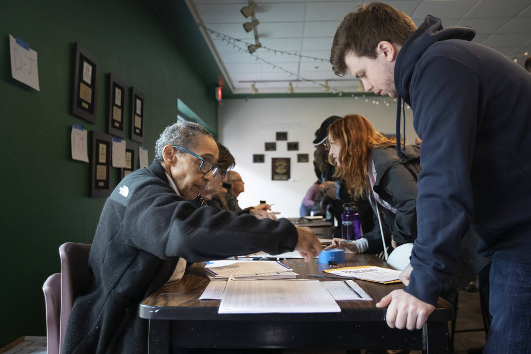 Conor Bredin, right, of Summerlin, checks in for the Nevada caucus at Palo Verde High School on ...