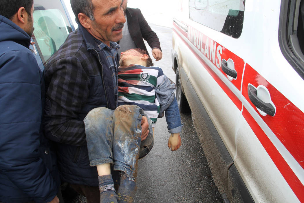 A man carries a wounded boy to an ambulance after an earthquake hit villages in Baskale town in ...