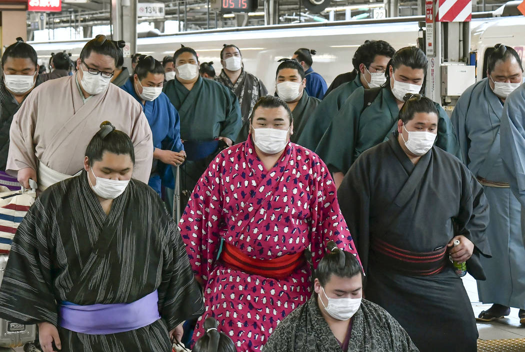 Sumo wrestlers wearing masks arrive at Shin Osaka railway station in Osaka, western Japan, Sund ...