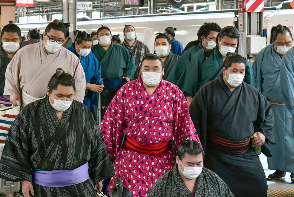 Sumo wrestlers wearing masks arrive at Shin Osaka railway station in Osaka, western Japan, Sund ...