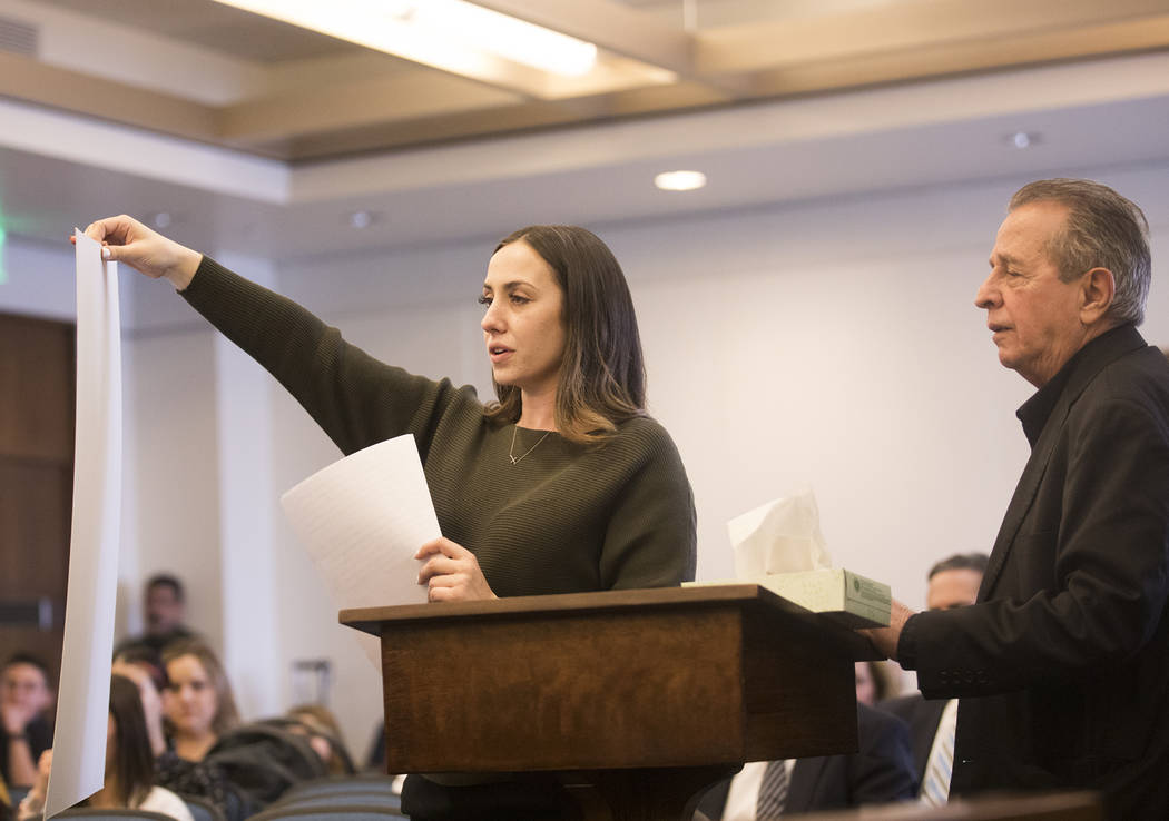 Allie Rossi, sister of A.J. Rossi, holds up a giant photo of A.J. while standing next to her fa ...