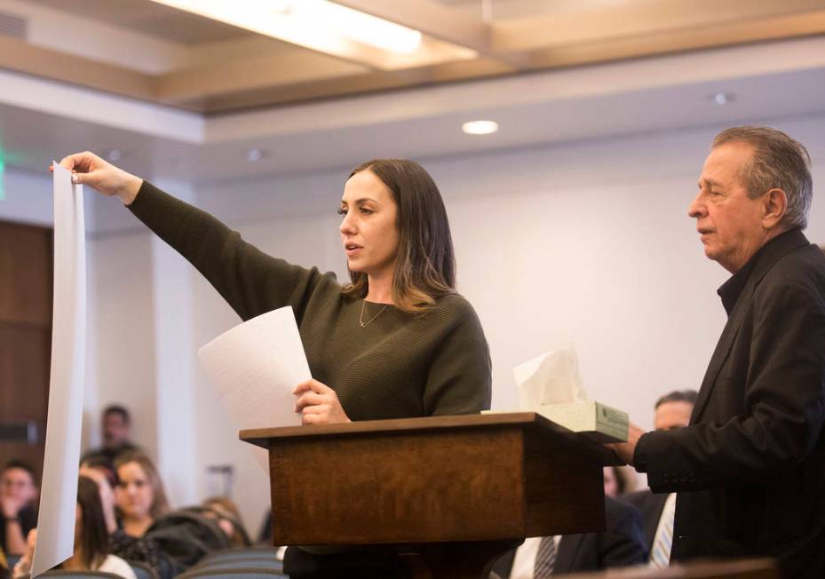 Allie Rossi, sister of A.J. Rossi, holds up a giant photo of A.J. while standing next to her fa ...