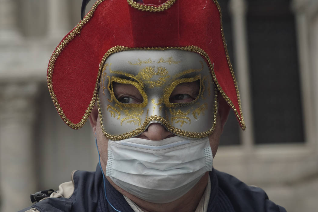 A Russian tourist dons both a carnival mask and a protective face mask as he visits St. Mark's ...