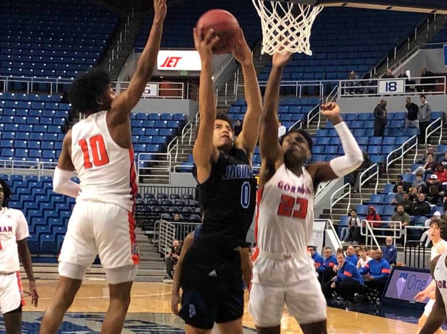 Desert Pines' Anthony Swift (0) goes for a basket between Bishop Gorman defenders Zaon Collins ...