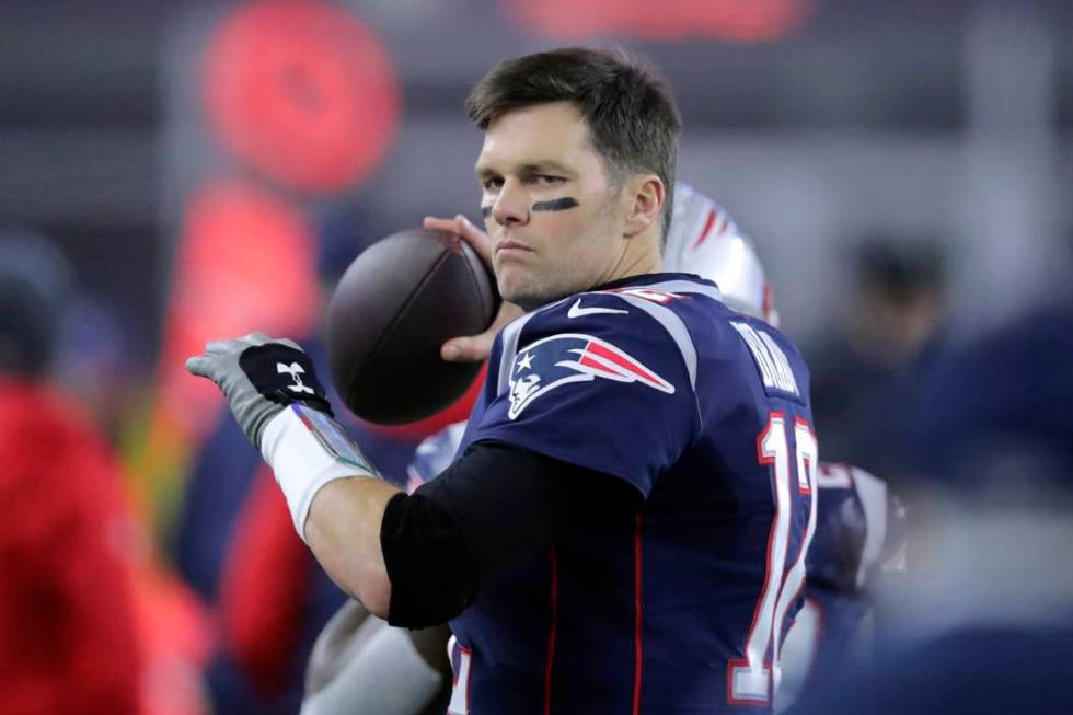 New England Patriots quarterback Tom Brady tosses the football on the sideline in the first hal ...