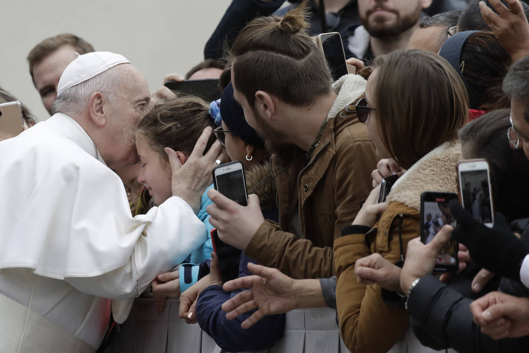 Pope Francis kisses a child in St. Peter's Square at the Vatican before leaving after his weekl ...
