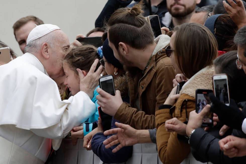 Pope Francis kisses a child in St. Peter's Square at the Vatican before leaving after his weekl ...