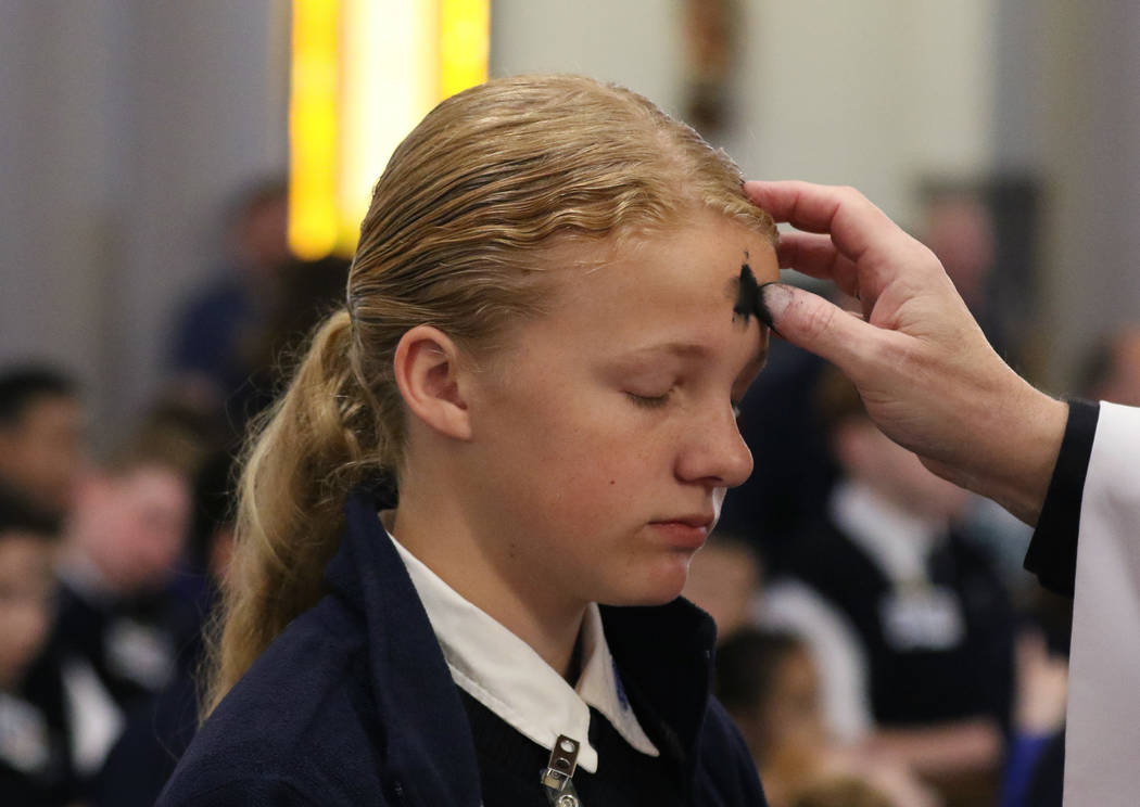 St. Viator Catholic School student Grace Yager, 12, receives ashes from the Rev. Dan Nolan duri ...