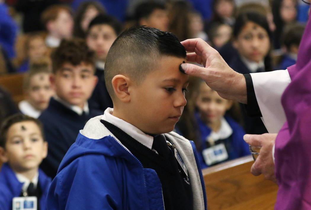 St. Viator Catholic Elementary School student Kaden Benito, 6, receives ashes from the Rev. Dan ...