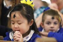 St. Viator Catholic Elementary School student Lilvin Nguyen, 7, prays after receiving ashes dur ...