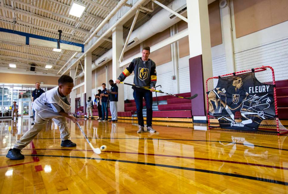 Nine-year-old Javon Williams, left, shoots as Golden Knights defenseman Brayden McNabb watches ...