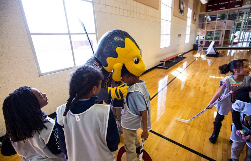 Golden Knights mascot Chance bites the head of Javon Williams, 9, during a youth street hockey ...