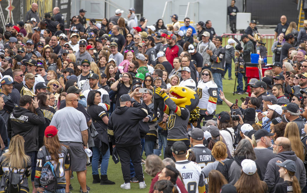 Chance the Gila Monster holds a baby dressed in team gear up to the crowd during the Vegas Gold ...